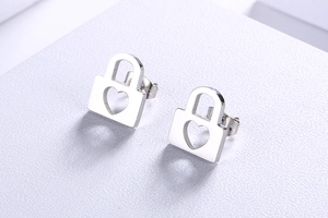 Macro view of silver hollow heart-shaped lock stud earrings with polished finish