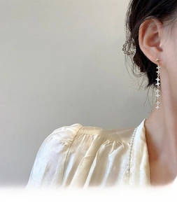 Detailed close-up of gold star dangle earrings with pavé zircons on a model