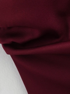 Gros plan sur la texture du tissu sergé rouge foncé montrant le tissage détaillé