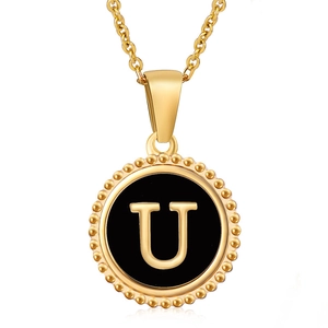 Macro shot of gold stainless steel necklace pendant with letter U on black enamel
