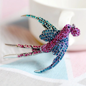 Primo piano dettagliato di una spilla a rondine con strass rosa e blu su metallo argento