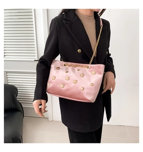 Detail of pink velvet tote with gold sun rivets and chain strap on a black blazer