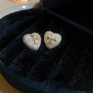 Macro shot of gold-plated heart stud earrings with zircon inlay and cross detail