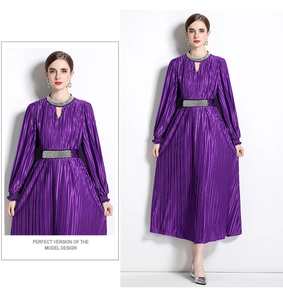 Detailed view of silver rhinestones and pleated texture on a purple luxury dress
