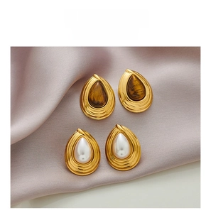 Detail of teardrop retro earrings with tiger eye stone and pearl on purple silk