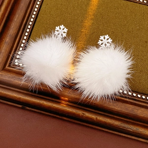 Close-up of winter snowflake earrings with white fluffy pompoms and pearl details