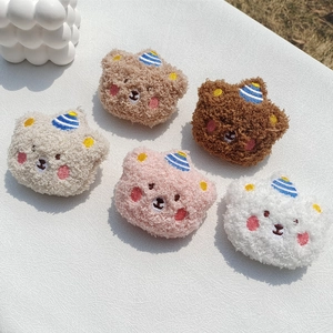 Close-up of colorful plush bear brooches with blue striped hats and embroidered faces