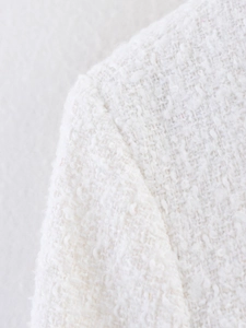 Gros plan sur l'épaule d'une veste en tweed blanc montrant la texture et les coutures fines