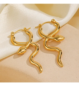 Detailed view of gold snake earrings on beige silk fabric and textured stone background
