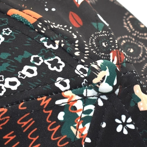 Detailed close-up of multi-color floral print stitching and peak button on black baseball cap
