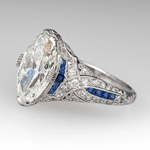 Art Deco ring featuring a large oval diamond and blue sapphire accents on a platinum band