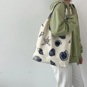 Detailed shot of large canvas tote bag featuring navy blue sea shells and starfish print