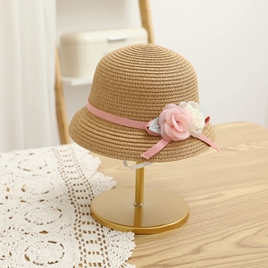 Close-up of girls straw hat featuring pink ribbon and delicate fabric flower detail