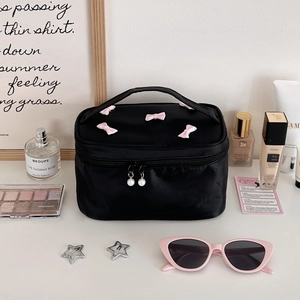 Detail of black satin makeup bag with pink bow and elegant pearl zipper pullers