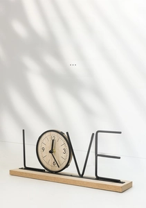 Macro shot of Nordic 'LOVE' wooden clock with a metal frame and minimalist wood grain face