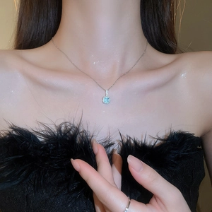 Detail of a square light blue gemstone necklace worn on a neck highlighting the silver chain