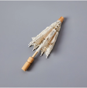 Macro shot of elegant white lace bridal umbrella with smooth vintage wooden handle