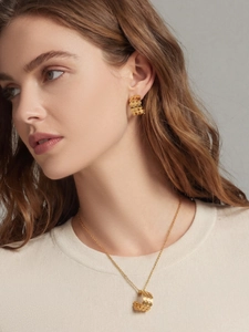 Détail d'un mannequin portant un collier et des boucles d'oreilles dorés en disque