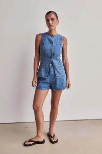 Dettaglio del gilet di jeans con bottoni monopetto e pantaloncini a vita alta abbinati