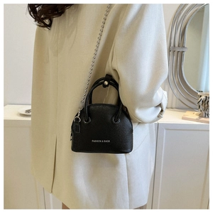 Close-up of black lychee texture shell bag with silver chain strap on model