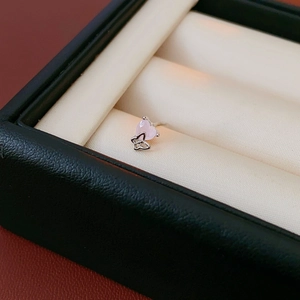 Macro view of silver butterfly stud earrings with pink heart zircon on velvet cushion