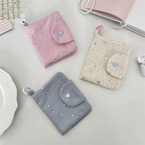 Detailed view of canvas star sequin card wallets in pink, beige, and blue with heart charms