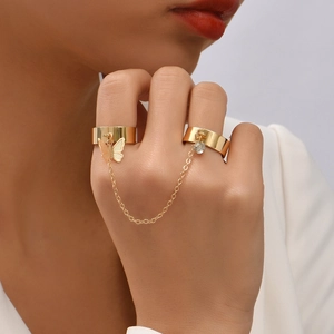 Detail view of a gold chain ring bracelet featuring butterfly and rhinestone charms on fingers