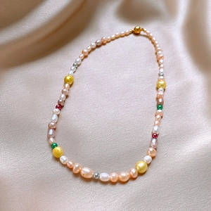Gros plan du collier de perles d'eau douce baroques multicolores sur tissu en soie champagne
