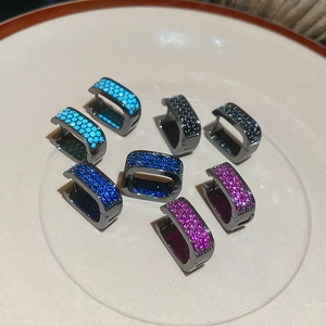 Macro detail of four pairs of square zircon huggie earrings in blue, pink, and black