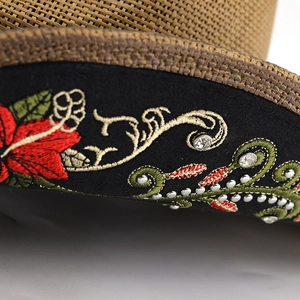 Close-up of floral embroidery with red hibiscus and rhinestones on woven straw hat