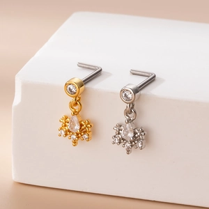 Detailed view of L-shaped gold and silver nose studs with zircon flower pendant