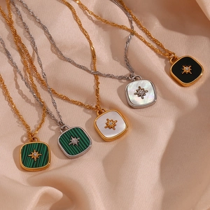 Detailed view of square star shell pendants with gold and silver chains on silk