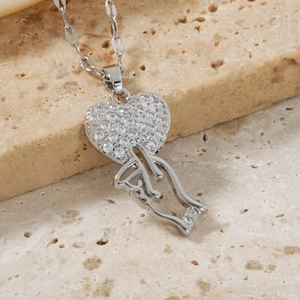 Macro shot of silver heart and finger pendant necklace with cubic zirconia on stone