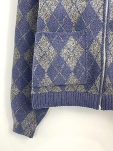 Detail of greyish blue diamond knit jacket showing metal zipper and ribbed texture