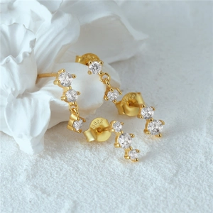 Macro detail of gold S925 sterling silver earring with three graded cubic zirconia stones