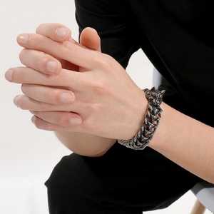 Détail du fermoir tête de loup et du bracelet chaîne tressée sur le poignet d'un homme