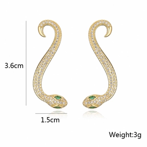 Detail showing 3.6cm gold snake earrings with sparkling cubic zirconia and green eyes