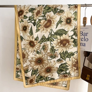 Detailed view of sunflower print scarf with yellow border and soft drape texture