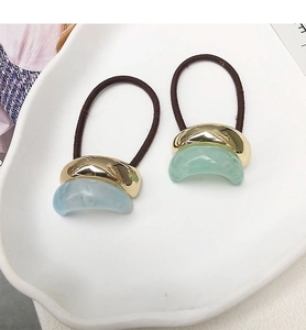 Detail of high-elasticity hair ties with gold metal base and marble resin accents