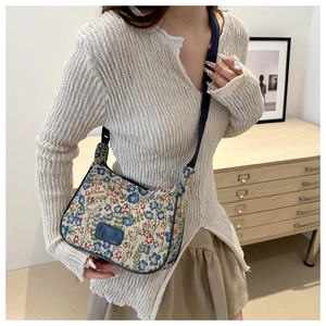 Detailed close-up of a blue floral pattern crossbody bag with a leather logo on the front