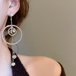 Detail of elegant gold drop earrings with star-moon charms and long crystal tassels