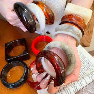 Macro shot of stylish resin bangles in marble and tortoiseshell patterns on wooden table