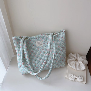 Detail of light blue quilted tote bag with floral patterns and chic bow decorations