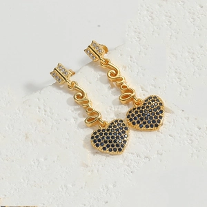 Detail of gold arrow heart earrings featuring vibrant blue pavé stones on stone surface