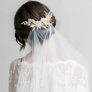 Close-up of bridal floral hair comb with pearls and sheer white tulle wedding veil