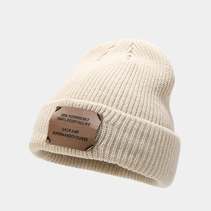 Close-up of thick ribbed knit texture on a beige beanie with brown rectangular patch
