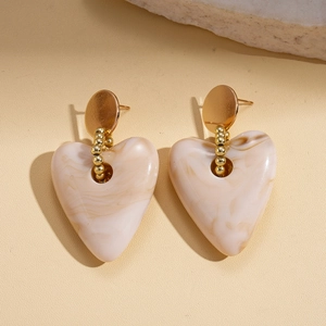 Detail of heart-shaped marble resin earrings with gold beads and circular studs