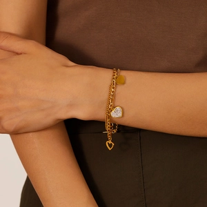 Dettaglio del bracciale dorato a doppio strato con ciondoli a cuore e cristalli brillanti