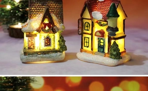 Close-up of LED glowing resin Christmas snow house miniatures with warm lights