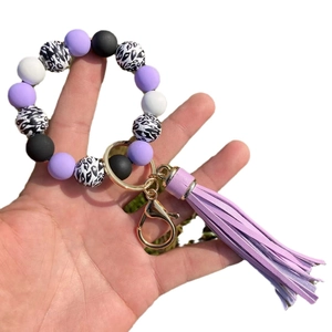 Beaded keychain bracelet with leopard print beads and purple tassel on white background